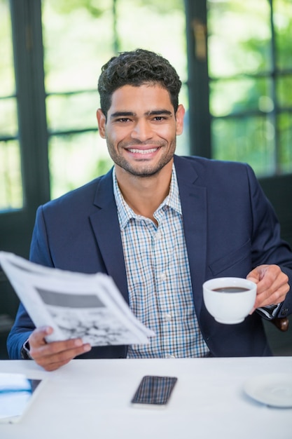 Empresário feliz segurando a xícara de café e jornal