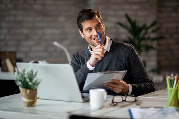 Empresario feliz trabajando en informes comerciales y gesticulando a alguien en la oficina