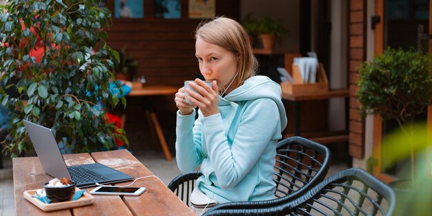 Empresario feliz trabajando con un teléfono y una computadora portátil en una cafetería en la calle