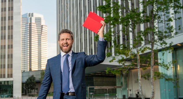 Empresario feliz en traje profesional con caja de regalo fuera de la bonificación de espacio de copia de oficina