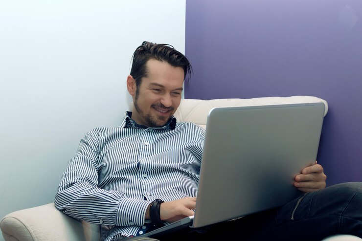 Foto empresario feliz usando la computadora mientras se relaja en el sillón