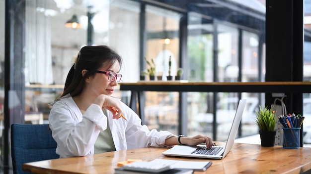 Empresário feminino trabalhando com computador portátil no local de trabalho moderno