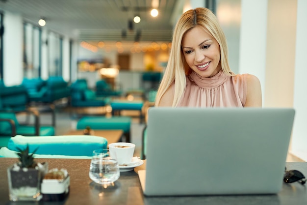 Empresário feminino usando computador enquanto toma café em um café