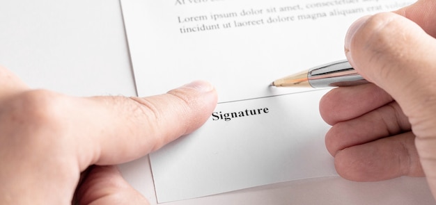 Empresario firmando un contrato con lápiz