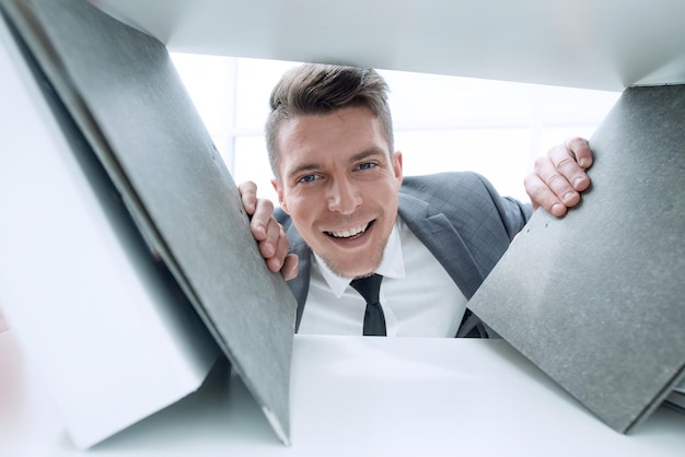 Empresario en el fondo sonriendo y sosteniendo documentos que se encuentran en un estante en un gabinete