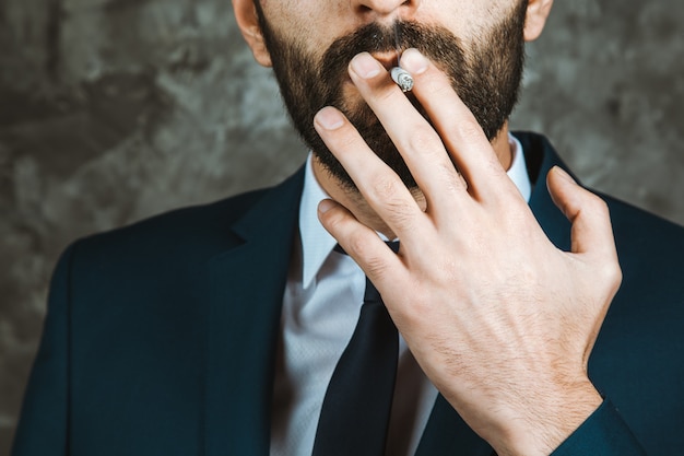 Empresario fumando un cigarrillo sobre fondo oscuro