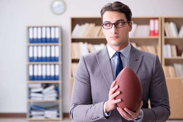 Empresario con fútbol americano en la oficina