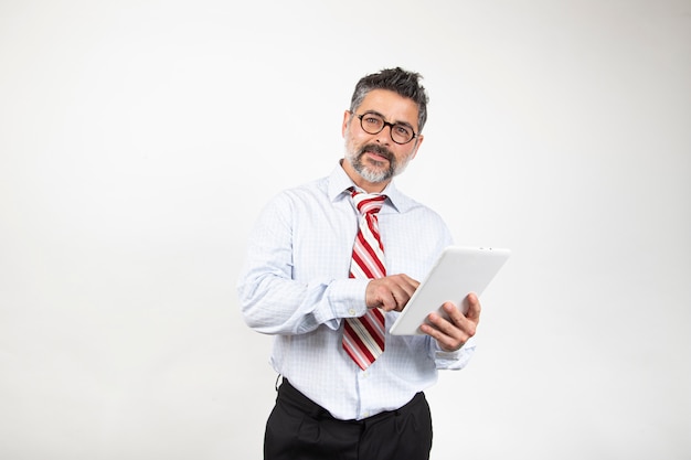 Empresario con gafas está utilizando una tableta digital y sonriente, aislado sobre fondo blanco.