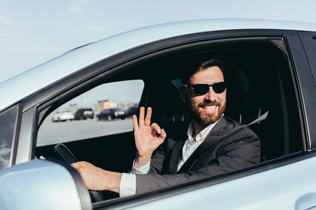 Empresario de gafas negras sentado al volante de un coche