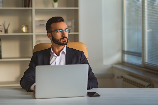 El empresario de gafas trabajando con una computadora portátil en el escritorio