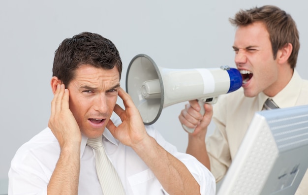 Empresario gritando a través de un megáfono a su colega