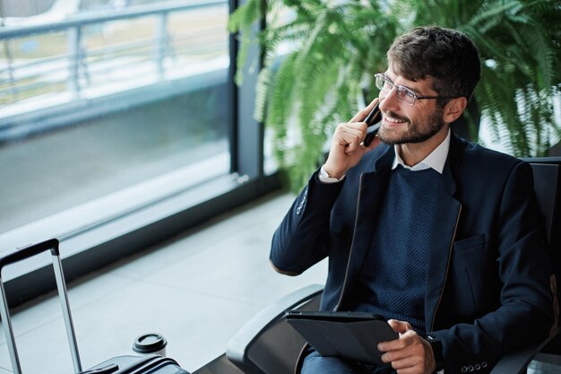 Empresario hablando por un smartphone desde la salida del aeropuerto h