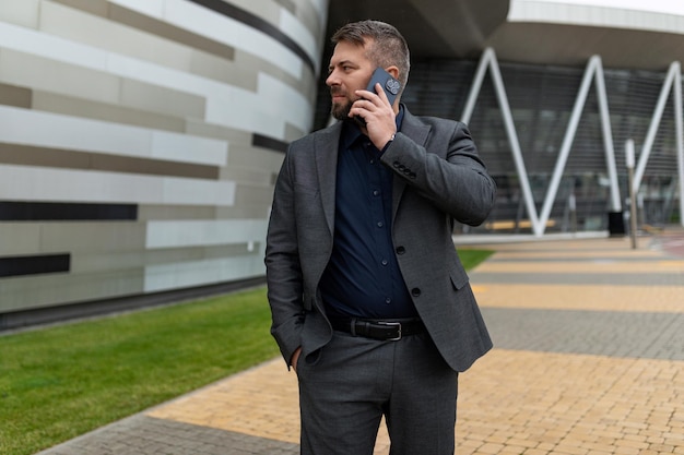 Empresario hablando por un teléfono móvil en un traje de negocios fuera de un edificio de oficinas