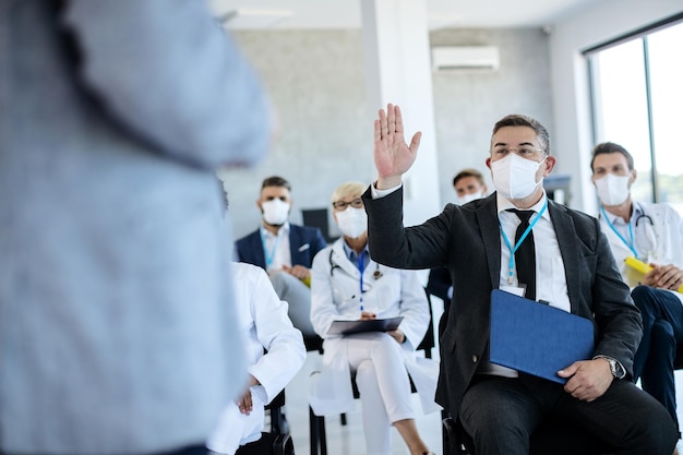 Empresario haciendo preguntas mientras asistía a un seminario durante la pandemia del coronavirus