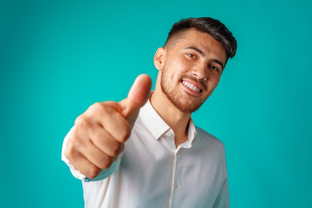 Empresario hispano guapo positivo mostrando el pulgar hacia arriba gesto