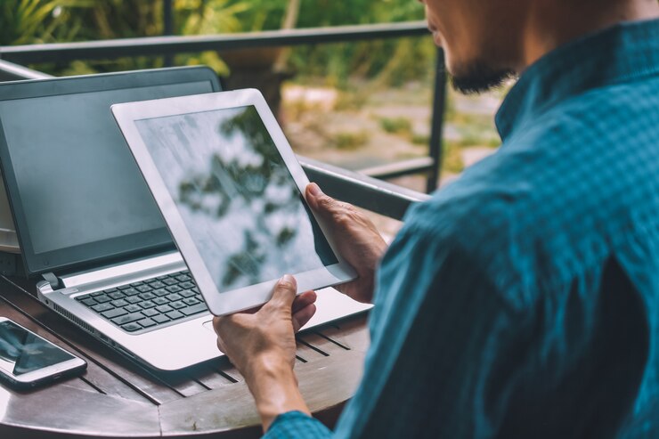 Foto empresario holding tablet con un móvil y una computadora portátil sobre la mesa
