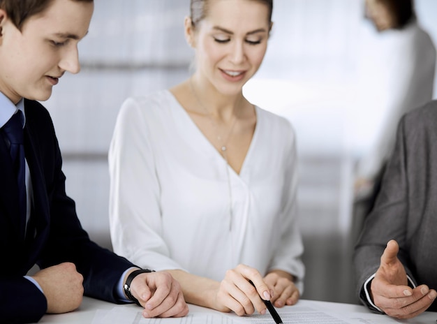 Empresário idoso e grupo de empresários discutindo contrato no escritório. Mulher e advogados trabalhando juntos na reunião. Trabalho em equipe e cooperação.