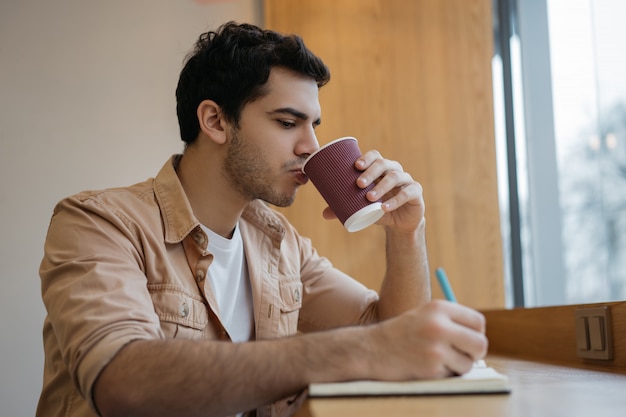 Empresário indiano tomando café no café, anotando, planejando o arranque