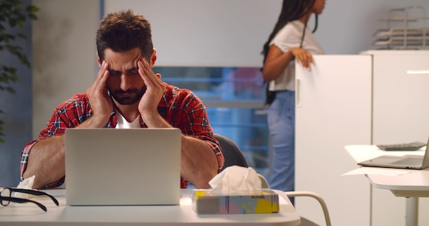 Foto empresario indio con ropa informal masajeando las sienes con dolor de cabeza sentado en el lugar de trabajo