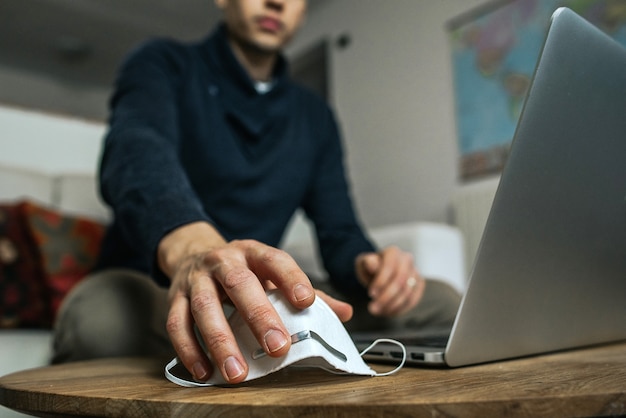 Empresário inteligente trabalhando em laptop em casa tomando máscara de proteção contra coronavírus