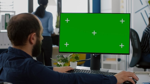 Empresário inválido paralisado sentado em uma cadeira de rodas com visor de chave de tela verde, digitando no computador enquanto a equipe trabalha em segundo plano. Colegas de trabalho multiétnicas planejando projeto de estratégia