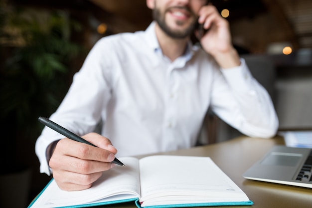 Empresario irreconocible escribiendo notas