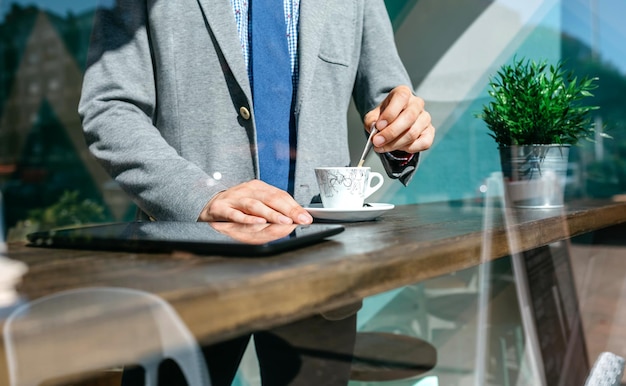 Empresario irreconocible revolviendo café en una cafetería