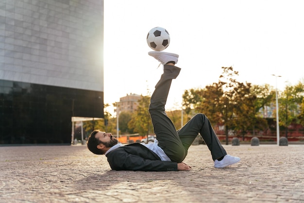 Foto empresário jogando com uma bola de futebol e fazendo truques de estilo livre