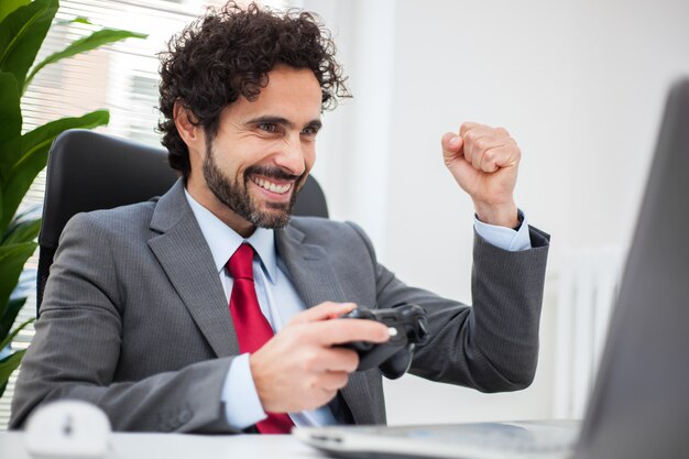 Empresário jogando videogame em seu escritório em vez de trabalhar