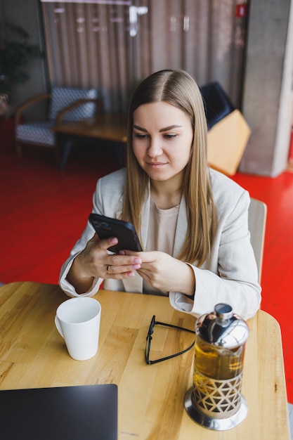 Empresário jovem e bonita usa smartphone para negócios compras on-line transferência de dinheiro finanças internet banking Mulher trabalhando em um café