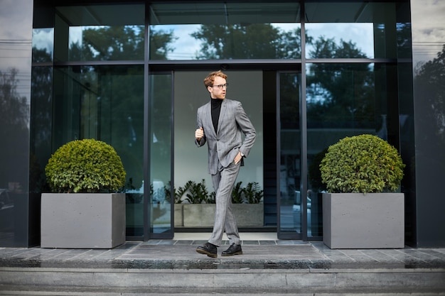 Empresário jovem empresário de terno formal cinza corre para uma reunião de negócios com investidores