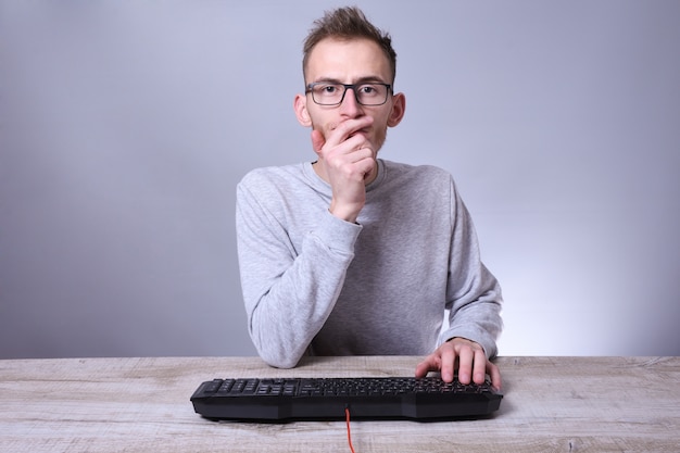 Empresário jovem nerd engraçado, homem trabalhando no computador. Digitando no programador de teclado em copos na frente do computador.