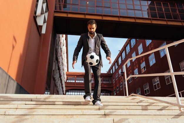 Empresario jugando con una pelota de fútbol y haciendo trucos de estilo libre