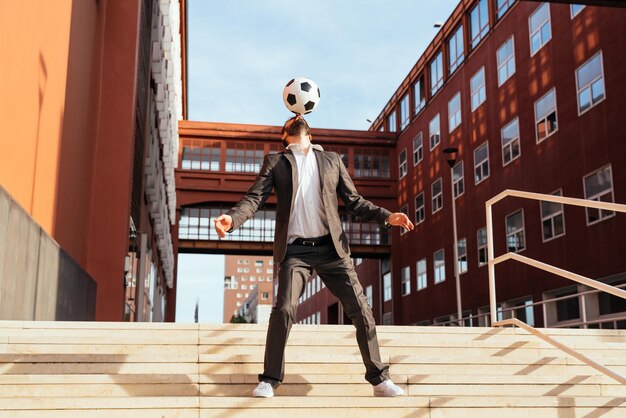 Empresario jugando con una pelota de fútbol y haciendo trucos de estilo libre