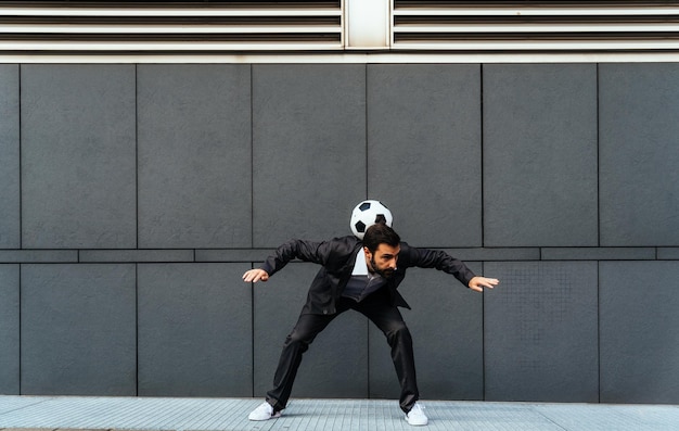 Empresario jugando con una pelota de fútbol y haciendo trucos de estilo libre