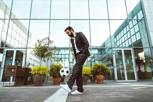 Empresario jugando con una pelota de fútbol y haciendo trucos de estilo libre