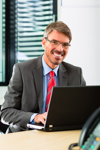 empresario con laptop en su oficina de negocios