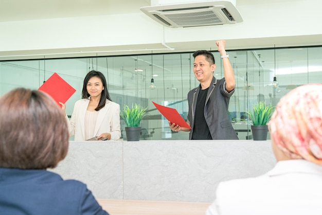 Empresario levantando la mano y el puño en celebración durante una reunión con el personal