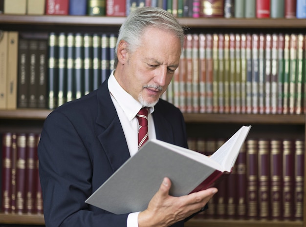 Empresario leyendo un libro en una biblioteca