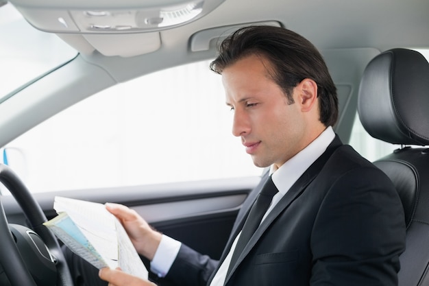 Empresario leyendo un mapa en su coche