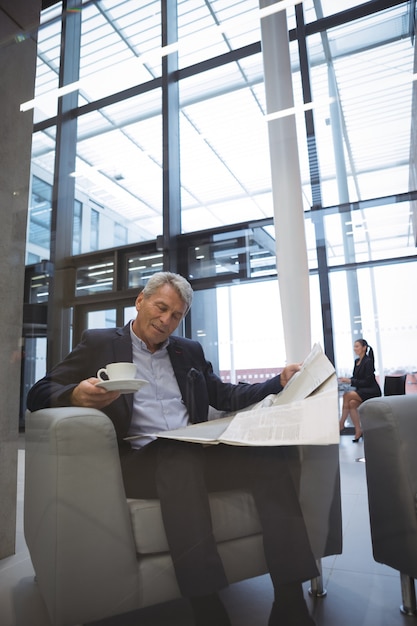 Empresario leyendo el periódico mientras toma un café