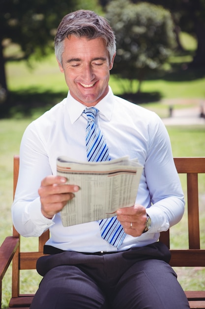 Empresario leyendo el periódico en el parque