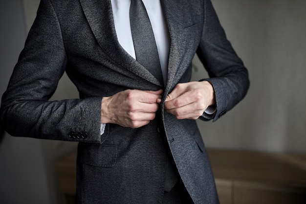 El empresario lleva una chaqueta, primer plano de manos masculinas, el novio preparándose en la mañana antes de la ceremonia de la boda