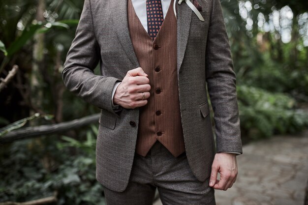 El empresario lleva una chaqueta, primer plano de manos masculinas, el novio preparándose en la mañana antes de la ceremonia de la boda