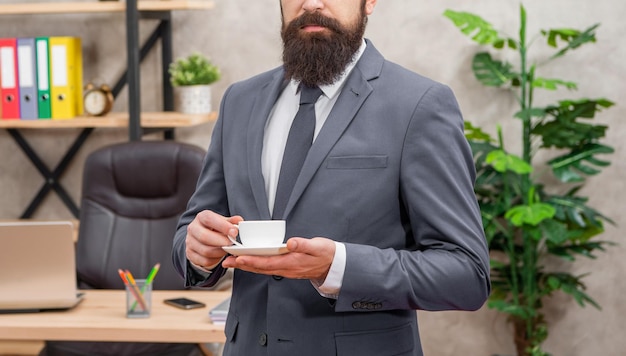 Empresario maduro recortado en chaqueta tomando café en el almuerzo de la oficina