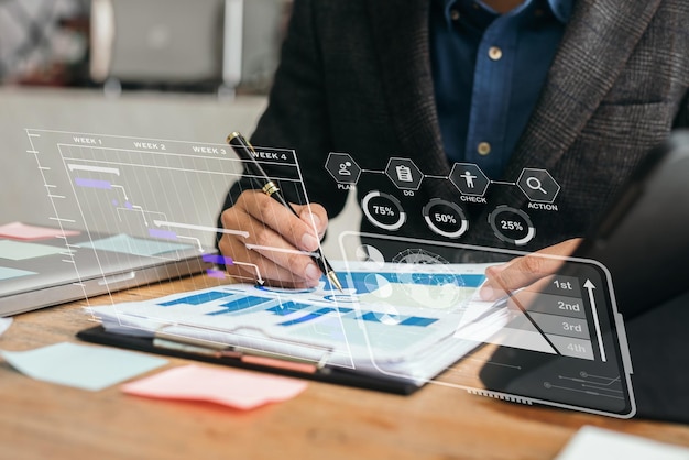 Empresario mano gerente de proyecto trabajando y actualizando tareas y diagrama de Gantt programación diagrama virtual con teléfono inteligente tableta y portátil en la oficina