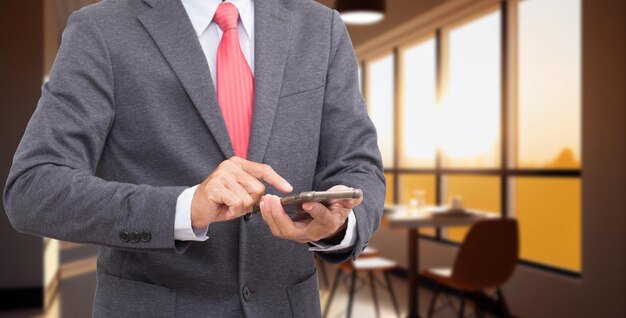 Empresario mano sujetando el teléfono móvil sobre fondo blanco.