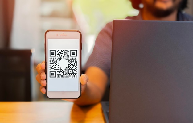 Empresario con la mano en el teléfono con código QR en la pantalla escaneando para iniciar sesión