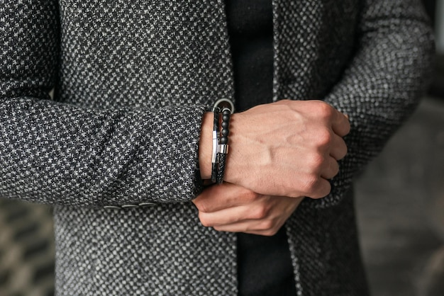 Empresário mantém as mãos juntas Homem em uma jaqueta cinza Acessórios masculinos elegantes de perto
