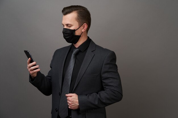 Empresario con máscara médica quirúrgica mediante teléfono celular